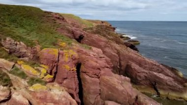 Arbroath kasabası yakınlarındaki su tarafından yok edilen kayalık bir sahilin insansız hava aracı görüntüsü..