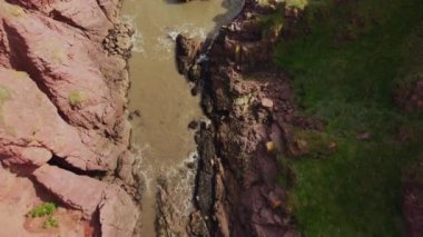 Dar bir koy boyunca kayalar arasında bir dronun uçuşu.