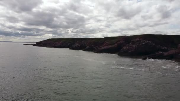 Drone view of the sea with a rocky shore with a cloudy sky in the background. — 비디오