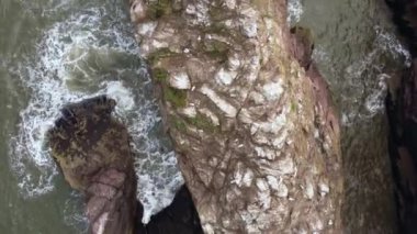 Top view from a drone on a protruding rock in a small bay.