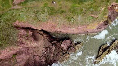 Yüksek kayalık sahilin ve aşağıdaki azgın okyanusun drone görüntüsü.