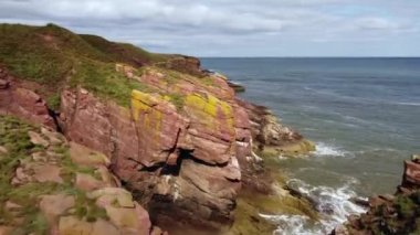Kuzey Denizi 'nin suları tarafından yıkanmış yeşil çimenlerle kayaların yanında çekim yapmak..