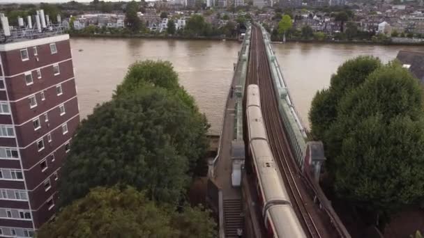A drone view of a London Underground train on the Fulham Railway Bridge. — Stock Video
