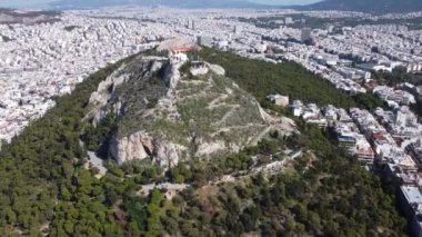 Güneşli bir havada Lycabettus Dağı 'nın etrafında uçan bir İHA ile çekim yapmak.