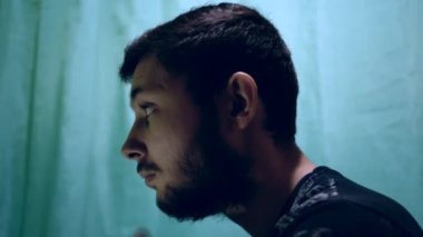 Banyoda tıraş olmadan önce yakışıklı bir doğulu çocuğu vurmak. Önplanda, mavi bir perdenin arkasında.