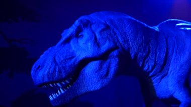 Tyrannosaurus keskin dişleriyle ağzını açıyor. Dinazor sergisinde neon ışıkları.