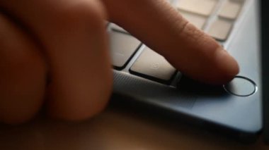 Adam dizüstü bilgisayarın kilidini parmağıyla açıyor. Çerçevede, ultraviyole klavyenin küçük bir parçası ve bir kişi eli var..