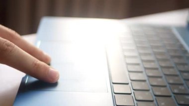 Küçük bir dizüstü bilgisayarla dokunmatik çekim yapmak. Çerçevede, dizüstü bilgisayarda çalışan bir adam parmaklarını gümüş bir dizüstü bilgisayarın dokunmatik bölmesinde gezdirir..