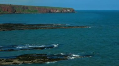 Güneşli bir günde sakin Kuzey Denizi 'ni yakalamak. Deniz yüzeyi İskoçya 'nın yüksek taş kıyılarına dayanır..