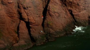 İki insanın deniz kenarındaki bir kayaya tırmandığı yakın çekim. Kuzey Denizi kıyısında güneşli bir günde çekim.
