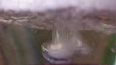 Yakın planda cam bir şişeyle nargile içerken. Şişede temiz köpüklü su var..