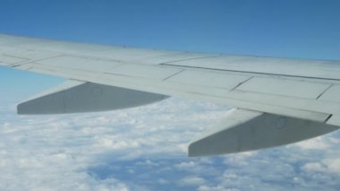 Arka planda dağınık bulutlarla uçağın penceresinden kanada bak. Bulutların üzerinde uçuşun güzel görüntüleri