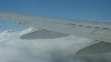 Entry of an airplane wing into thick white clouds. Beautiful shots in the daytime from the window of a passenger plane.