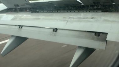 Havaalanındaki pistte araba sürerken bir uçak kanadının görüntüsü. Kalkıştan önce flaplar ayarlandı..