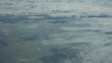 Bulutların üstündeki bir uçak penceresinden vurulmuş. Yerde bir bulut gölgesi var.