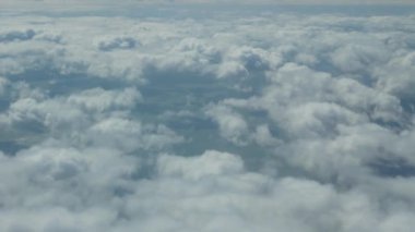 Yerin üstünde beyaz bulutlardan oluşan bir uçaktan çekim yapmak. Çerçeve güneşli bir günde yavaşça hareket eder..