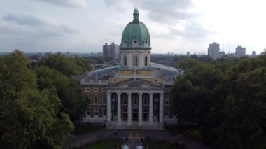 Londra 'daki İmparatorluk Savaş Müzesi' nin girişinin insansız hava aracı görüntüsü. Arka planda güzel bulutlu bir gökyüzü ve İngiliz başkentinin gökdelenleri var..