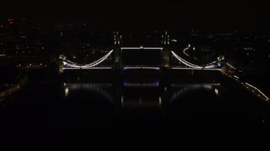 Arkasında şehrin ışıkları olan parlayan Kule Köprüsü 'nün insansız hava aracı görüntüsü. Gecenin ünlü simgesinin inanılmaz manzarası.