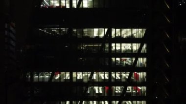 İnsansız hava aracı gece Londra şehrindeki bir gökdelenin penceresinin yanında uçuyor. Gecenin köründe gökdelenin detaylı görüntüsü.