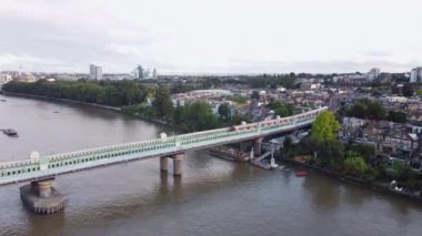 Londra 'daki Fulham Demiryolu Köprüsü' nden Thames Nehri 'nin insansız hava aracı görüntüsü. Eylül ortasında bulutlu bir havada çekim. Kıyıda alçak bir bina var..
