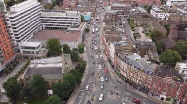 Köprünün önündeki yol ayrımının ve aktif araba trafiğinin drone görüntüsü. Binaların ve evlerin çatılarını görebilirsin..