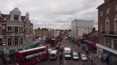 Çift katlı kırmızı otobüslü bir trafik sıkışıklığının insansız hava aracı görüntüsü. Wimbledon 'da alçak binalar.