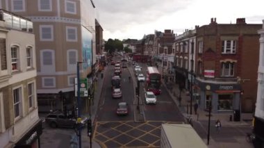 A drone view of a busy street in London in mid-September. Beautiful houses, a variety of shops and pedestrians with cars.