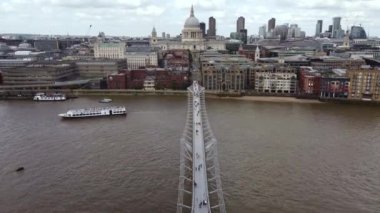 Drone view of London Millennium Footbridge across the Thames. People are walking on the bridge.