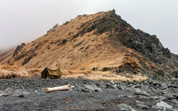 帐篷是由山下岩石海岸的防水油布制成的 奥霍次克海岸边的小帐篷在大雾中被风暴吹过 俄罗斯 — 图库照片