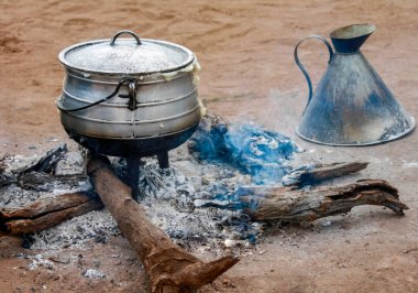 Köyün bahçesindeki kamp ateşinde geleneksel mısır lapası pişirme. Mısır unu lapası, Afrika 'daki bir yerleşim bölgesinde kömürün üstünde pişirilir.. 