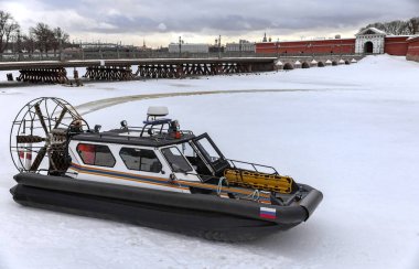 Peter ve Paul Kalesi 'nin arka planına karşı St. Petersburg' daki buz nehri üzerindeki arama kurtarma ekibinin amfibik botu. Kış aylarında buz nehrinin karlı yüzeyinde aero motorlu yüksek hızlı kurtarma botu.. 