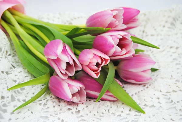 Primo piano di mazzo di tulipani rosa su un centrino all'uncinetto bianco in stile brocante classico — Foto Stock