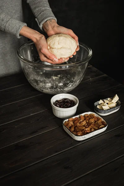 Baking sweet cottage cheese braided bread with raisins and jam. Ingredients on a wooden table. Holding the dough in hands. Lifestyle image.
