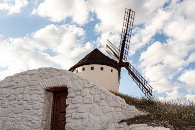 Tipik bir İspanyol yel değirmeni mağaranın üstündeki tepede. Arkaplanı mavi gökyüzü ve bulutlarla