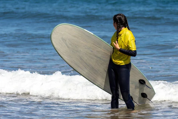 Photo with copy space of a distracted young woman carrying a surfboard on the beach