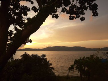 Yaz tatili için adalar ve ağaçlarla deniz sahilinde güzel bir gün batımı..