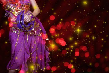 Göbek Dansçısı mor dans kostümü giyiyor. Renkli bokeh ile yakın plan.