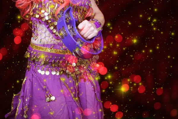 Göbek Dansçısı mor dans kostümü giyiyor. Renkli bokeh ile yakın plan.