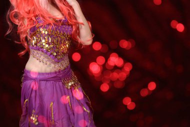 Göbek Dansçısı mor dans kostümü giyiyor. Renkli bokeh ile yakın plan.