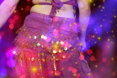Göbek Dansçısı mor dans kostümü giyiyor. Renkli bokeh ile yakın plan.
