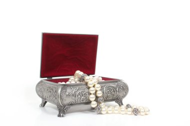 Açık renkli arka planda inci kolyeli mücevher kutusu.