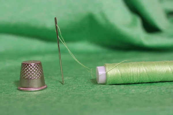 Spool of Green Thread, Thimble and Needle on Green Fabric — Stock Photo, Image