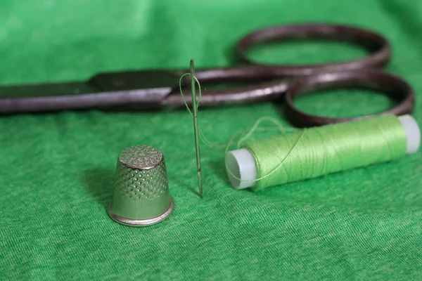 Spool από πράσινο νήμα, δαχτυλήθρα και βελόνα σε πράσινο ύφασμα — Φωτογραφία Αρχείου