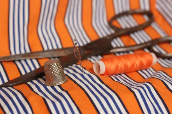 オレンジと白のストライプ生地にオレンジの糸とシンブル — ストック写真