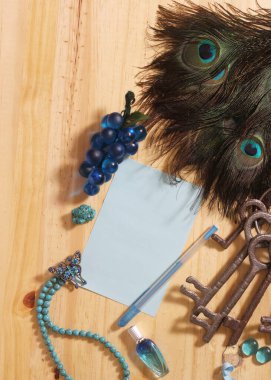 Tahta Masa Üzerinde Not ve Kalem Etrafı Tavuskuşu tüyleri ve Mücevherleriyle çevrili