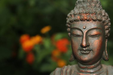 Bahçedeki bulanık çiçekli Buda Heykeli