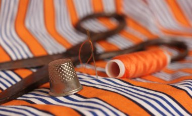 Turuncu ve beyaz çizgili kumaş üzerinde turuncu iplik ve yüksük makarası