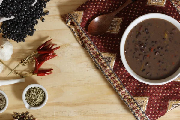 Baharatlı ve kuru fasulyeli, ahşap masadaki siyah fasulye. Kasenin altında eski kumaş