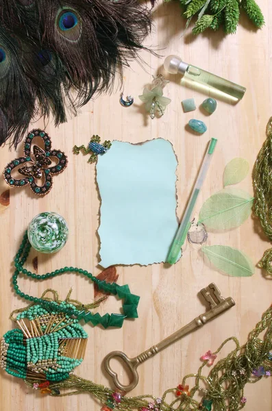 Yeşil Mücevherler ve Tavuskuşu tüyleriyle çevrili Eski Yanmış Kağıt ve Antika Anahtar Ahşap Arkaplanda