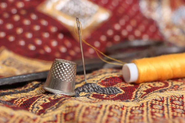Thread dourado e dedal em tecido vintage do Oriente Médio — Fotografia de Stock